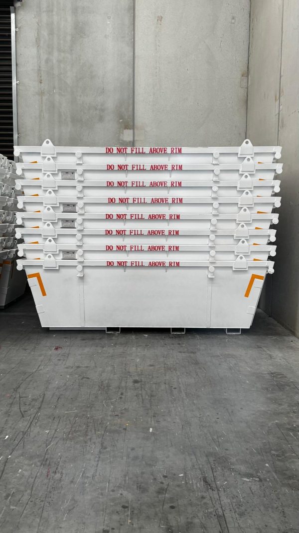 Stack of white industrial containers with rims stacked in a warehouse, red text reads 'DO NOT FILL ABOVE RIM' on each level.