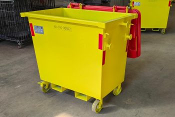 Yellow wheeled industrial waste bin with a red hinged lid in a warehouse setting.